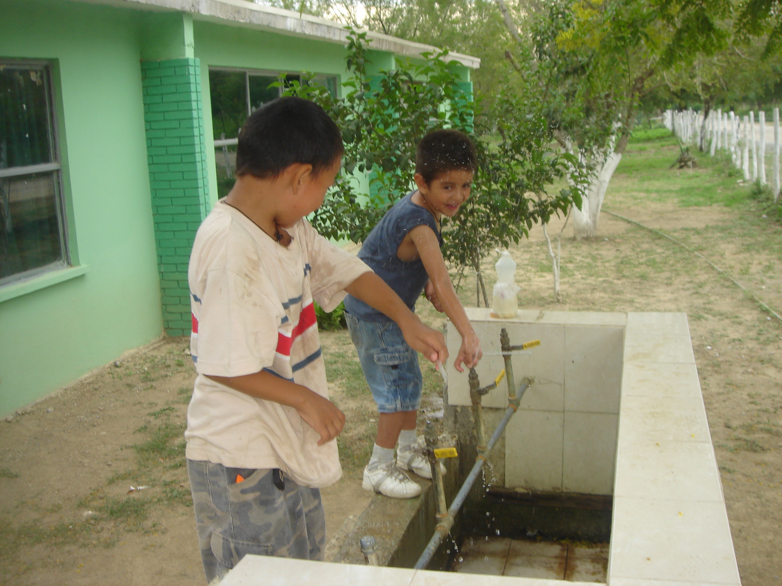 Mexican children playing in the drinking fountain at their school